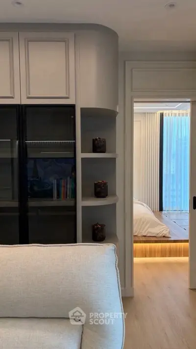Modern living room with built-in shelves and view into cozy bedroom