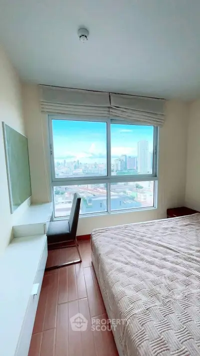 Bright bedroom with large window offering stunning city view, featuring cozy bed and modern furniture.