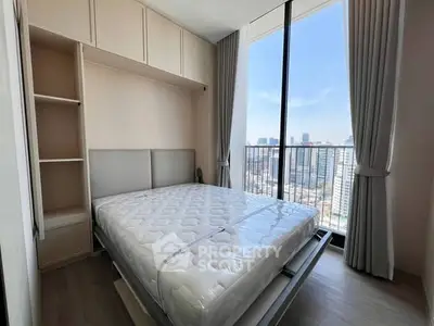 Modern bedroom with large window offering stunning city view, featuring a comfortable bed and ample storage space.