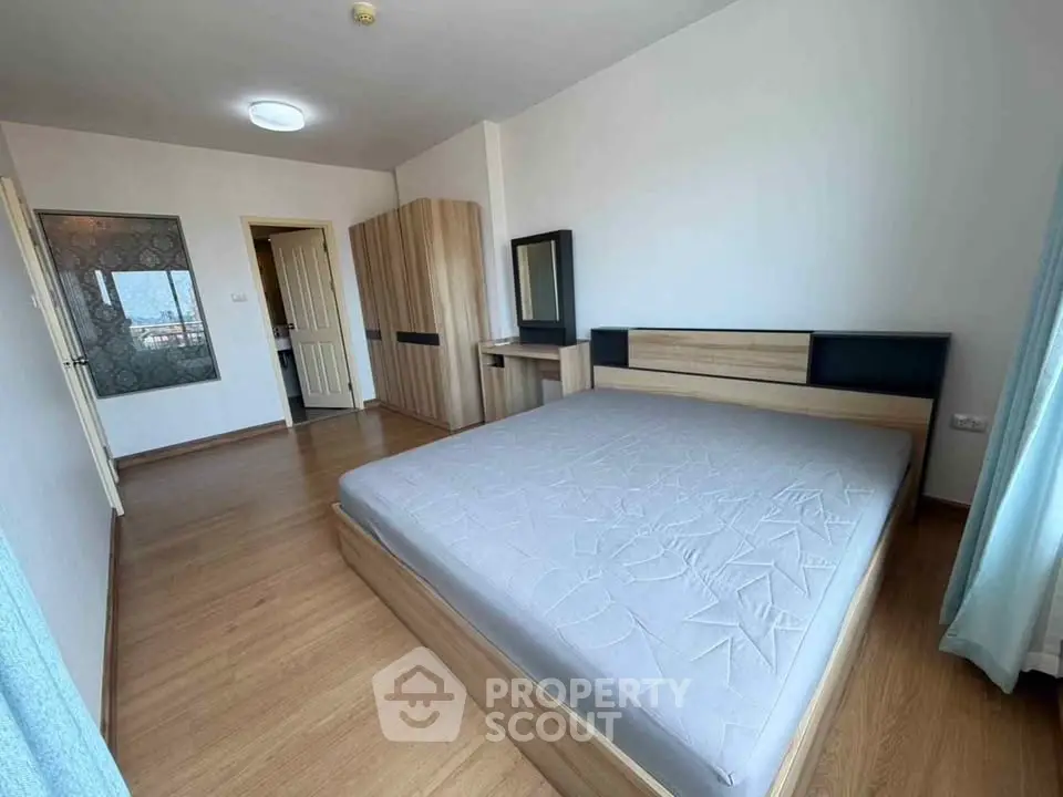 Spacious bedroom with modern wooden furniture and large window for natural light.