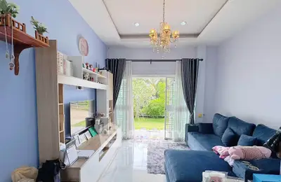 Charming living room with elegant chandelier and plush blue sofa, opening to a lush garden view.
