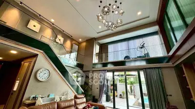 Luxurious modern living room with high ceilings and mezzanine overlooking a stylish outdoor pool area.