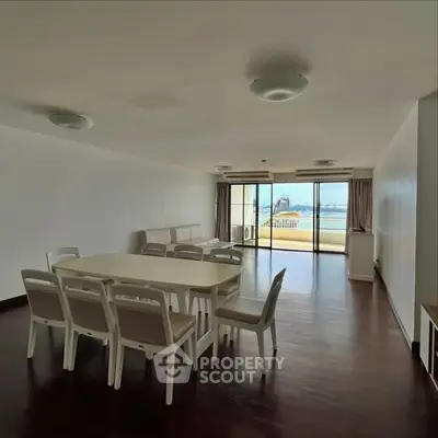 Spacious living room with dining area and ocean view balcony in modern apartment.