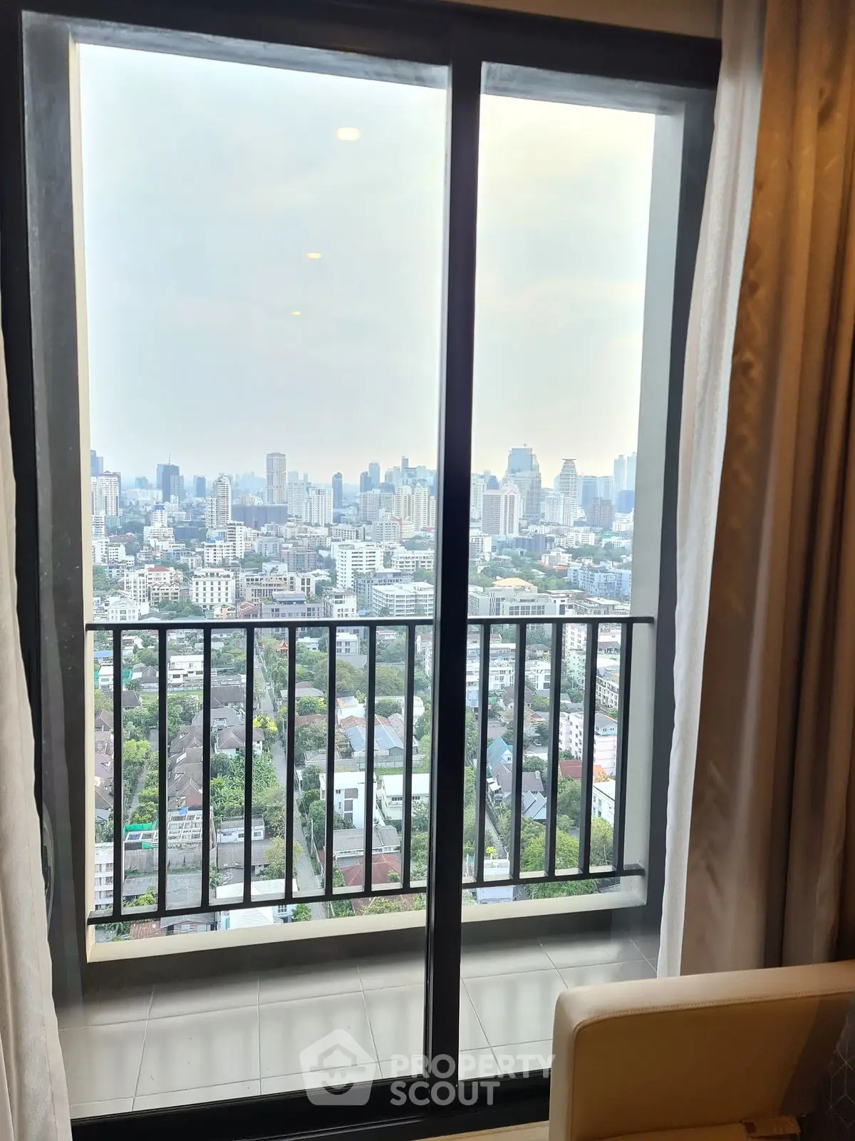 Stunning cityscape view from high-rise apartment balcony with glass doors.