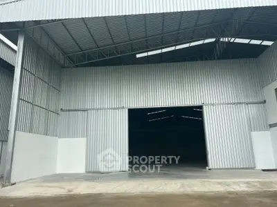 Spacious industrial warehouse with high ceilings and large entryway, ideal for storage and logistics.