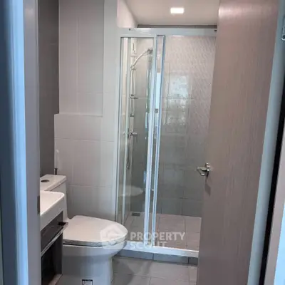 Modern bathroom with glass shower enclosure and sleek fixtures in a contemporary apartment.