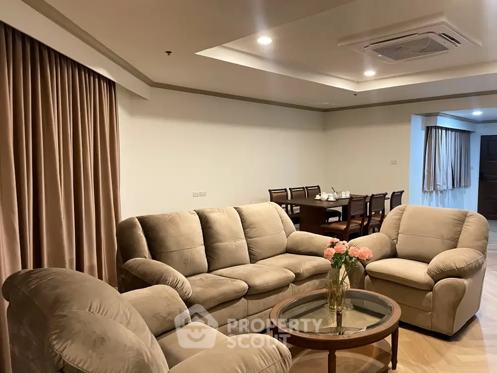 Spacious living room with plush seating and elegant dining area in the background, perfect for entertaining and relaxation.