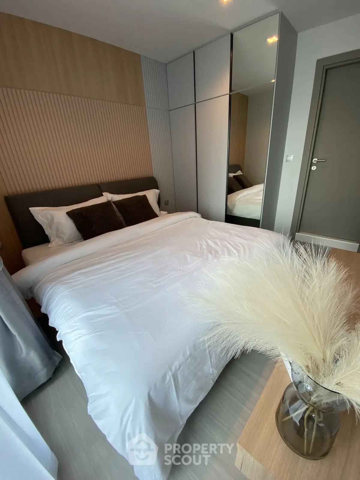 Modern bedroom with stylish decor and mirrored wardrobe in a cozy apartment.