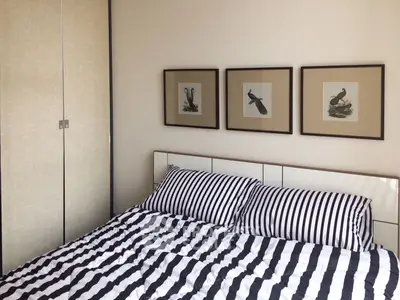 Cozy bedroom with striped bedding and framed bird art, perfect for relaxation.