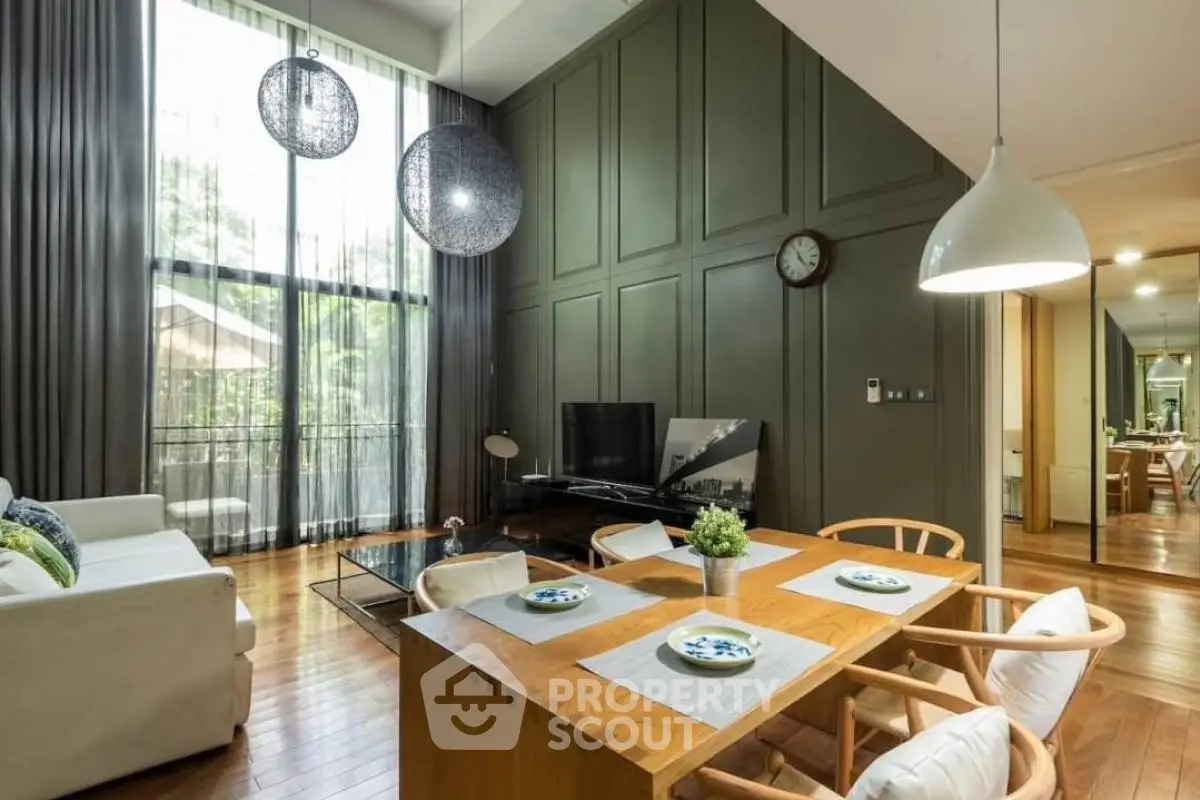 Spacious living room with high ceilings, modern decor, and large windows offering natural light and garden view.