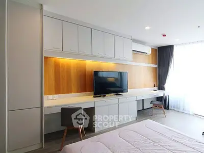 Modern bedroom with built-in desk and TV, featuring sleek cabinetry and natural light.