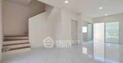 Spacious modern living area with sleek staircase and large windows for natural light.