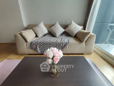 Stylish living room with cozy beige sofa and elegant coffee table, featuring a vase of pink roses, perfect for relaxation.
