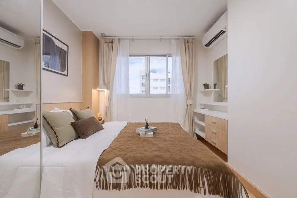 Cozy bedroom with modern decor and ample natural light, featuring a stylish bed and elegant furnishings.