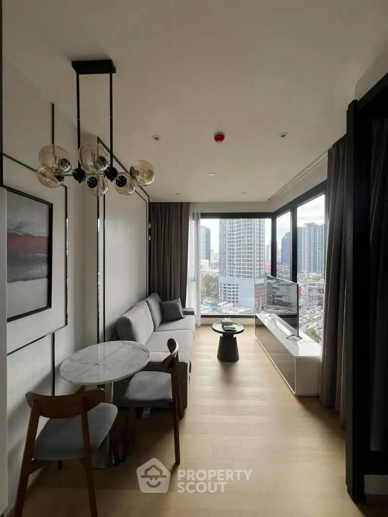 Modern living room with city view, stylish furniture, and large windows in a high-rise apartment.