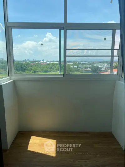 Bright enclosed balcony with large windows offering a panoramic city view.