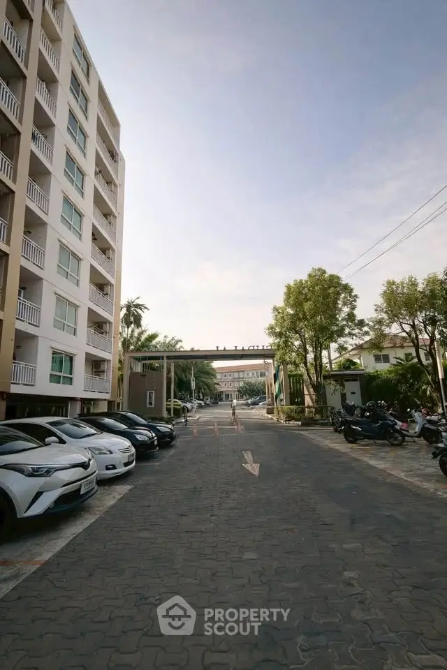 Modern apartment building with parking area and lush greenery, ideal for urban living.