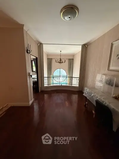 Elegant interior with hardwood floors and large window offering natural light, perfect for a stylish living space.