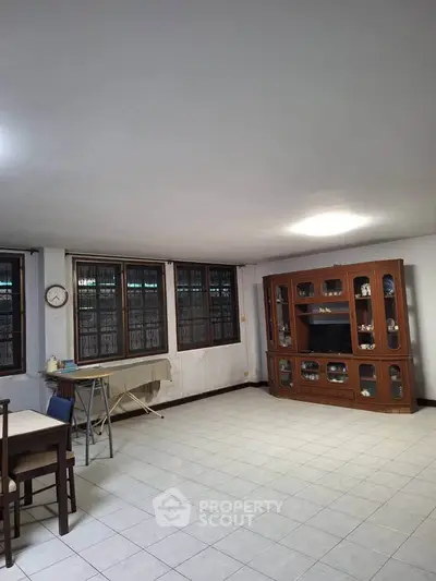 Spacious living room with tiled floor and wooden furniture, perfect for family gatherings.