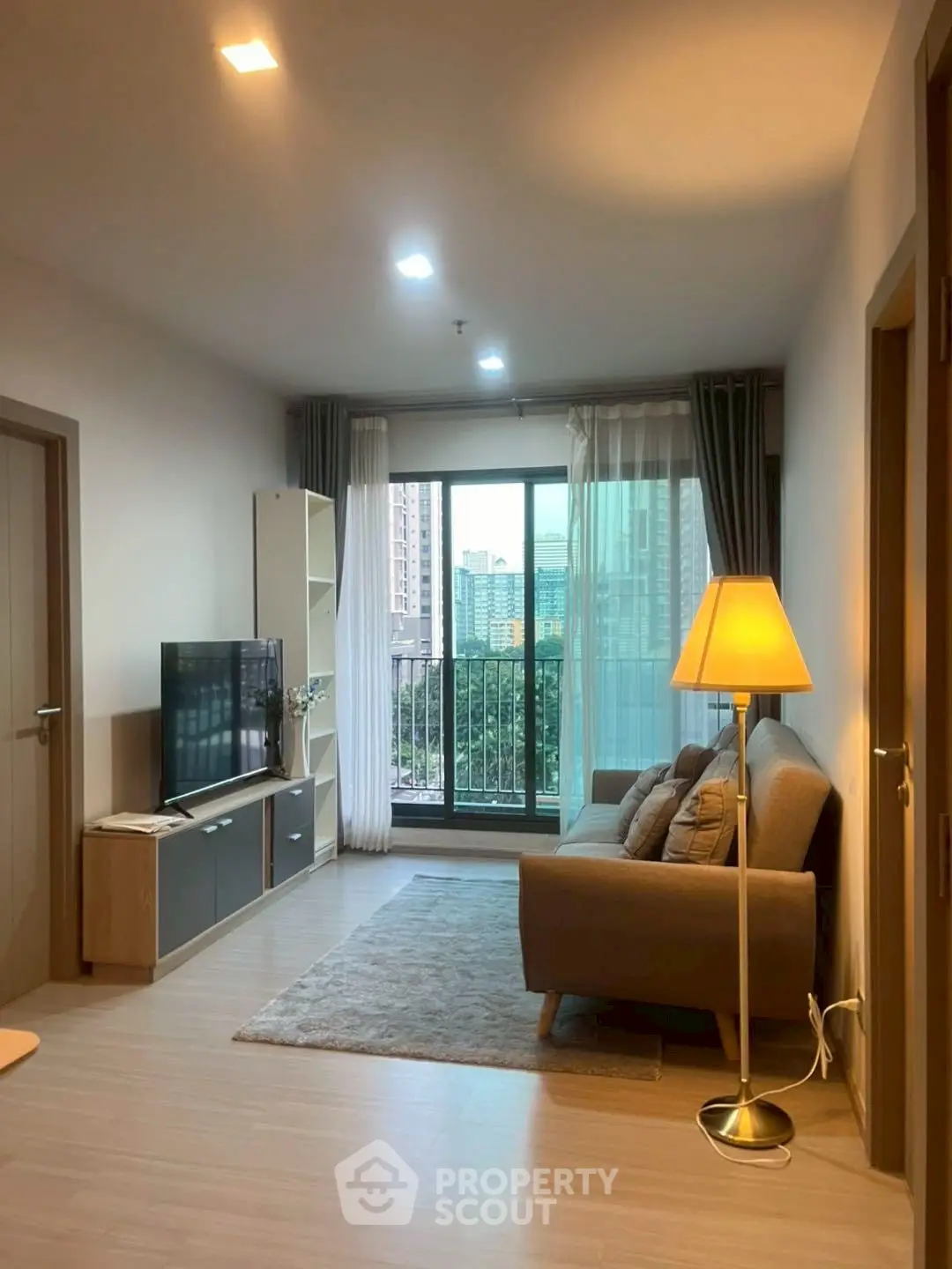 Cozy living room with modern decor and city view balcony.