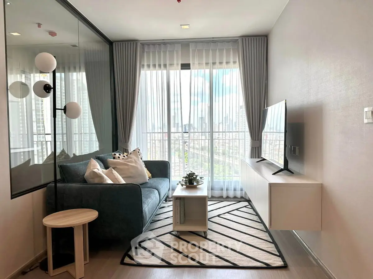 Modern living room with large window and city view, featuring stylish furniture and decor.