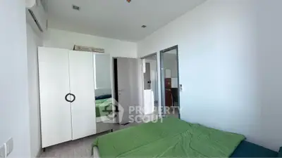 Modern bedroom with green bedding and sleek white wardrobe in a bright apartment.