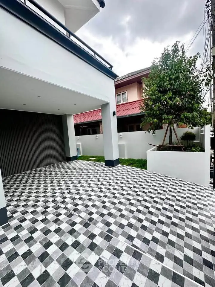 Spacious modern driveway with checkered tiles and lush greenery