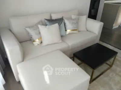 Modern living room with elegant white sofa and stylish cushions, featuring a sleek black coffee table.