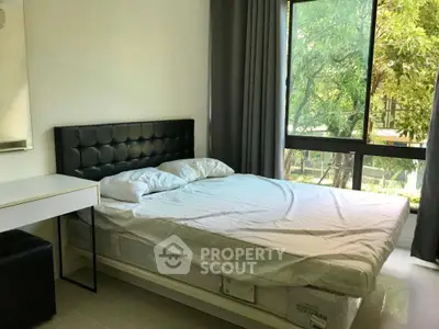 Spacious bedroom with large window and modern furnishings, offering a serene view of lush greenery.