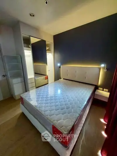 Modern bedroom with stylish lighting and mirrored wardrobe in a cozy apartment.