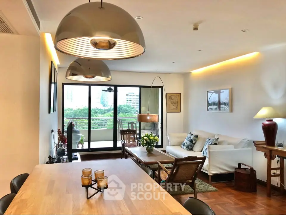 Spacious living room with elegant decor and large windows opening to a lush balcony view.