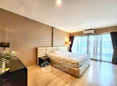 Spacious bedroom with modern decor and large windows offering natural light.