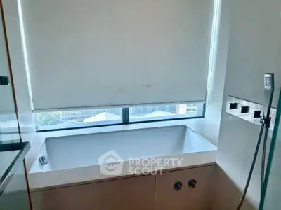 Luxurious bathroom with a modern bathtub and large window offering natural light.