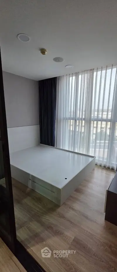 Spacious bedroom with large windows and modern flooring, perfect for natural light lovers.