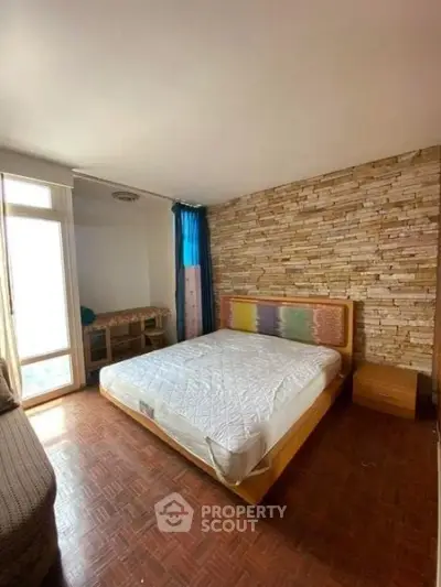 Cozy bedroom with stone accent wall and large window for natural light