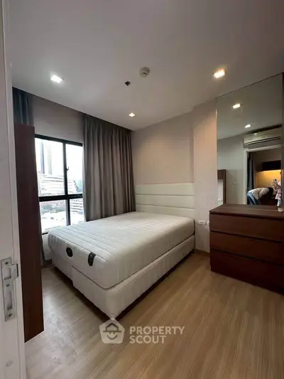 Modern bedroom with large window and stylish furniture in a contemporary apartment.