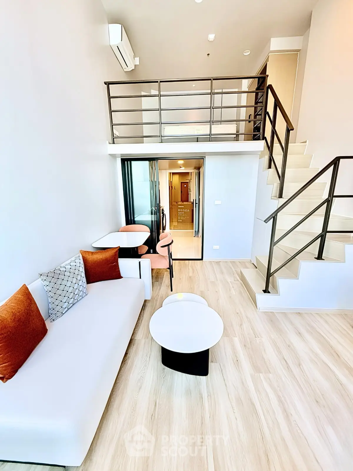Modern duplex living room with stylish furniture and loft area, featuring sleek design and ample natural light.