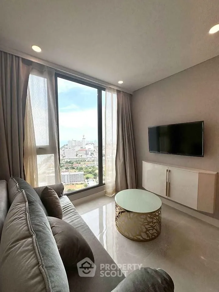 Modern living room with stunning city view, featuring sleek furniture and large windows.