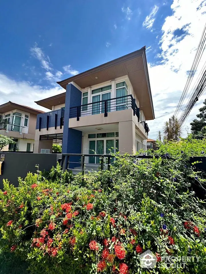 Modern two-story house with lush garden and blue sky backdrop