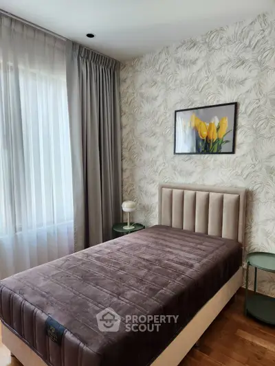 Cozy bedroom with elegant decor and natural light, featuring a plush bed and stylish side tables.