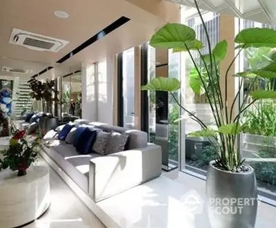 Sunlit modern living room with lush indoor plants, sleek white furniture, and floor-to-ceiling windows offering a serene view.