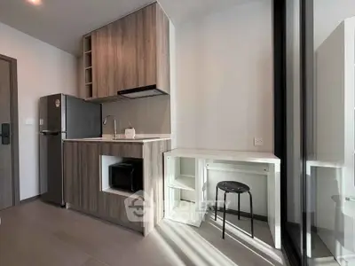 Modern kitchen with sleek cabinetry and compact design, featuring a fridge and microwave for efficient living.