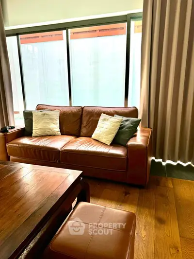 Cozy living room with leather sofa and wooden flooring, perfect for relaxation.