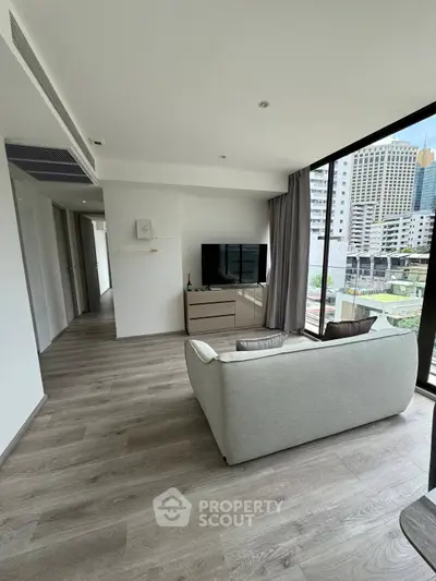 Modern living room with sleek design and city view, featuring a cozy sofa and large TV.