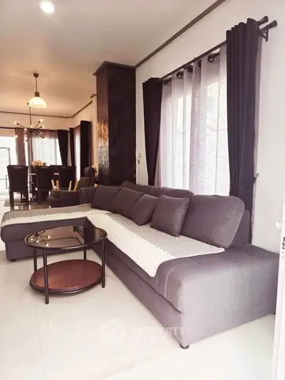 Modern living room with stylish gray sofa and elegant dining area in open layout.