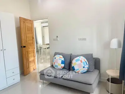 Modern living room with cozy gray sofa and colorful cushions, wooden door, and sleek white wardrobe.