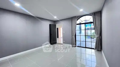 Spacious modern room with large arched window and sleek tile flooring