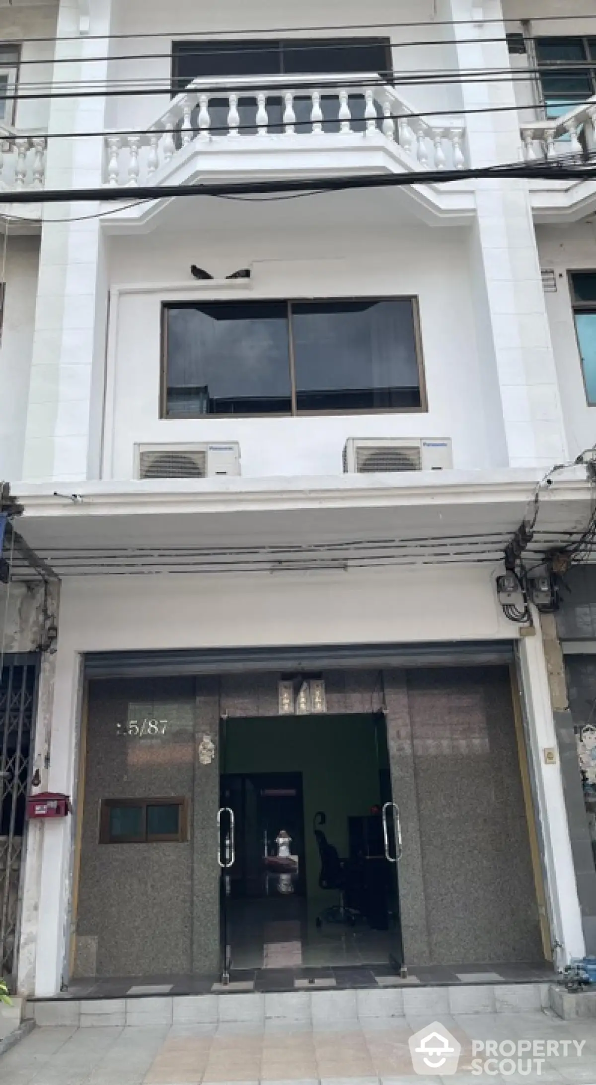 Charming three-story building with modern facade and balcony, ideal for commercial or residential use.