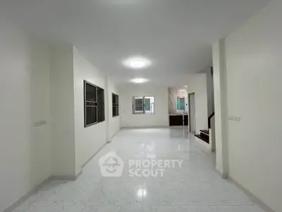 Spacious open-plan living area with modern white tile flooring and ample natural light.