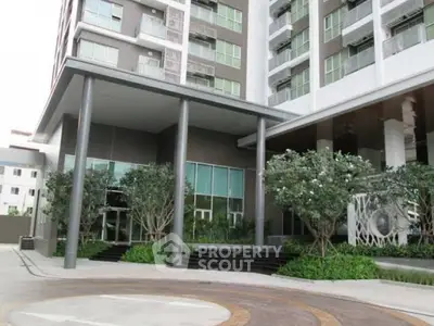 Modern apartment building entrance with landscaped greenery and sleek design.